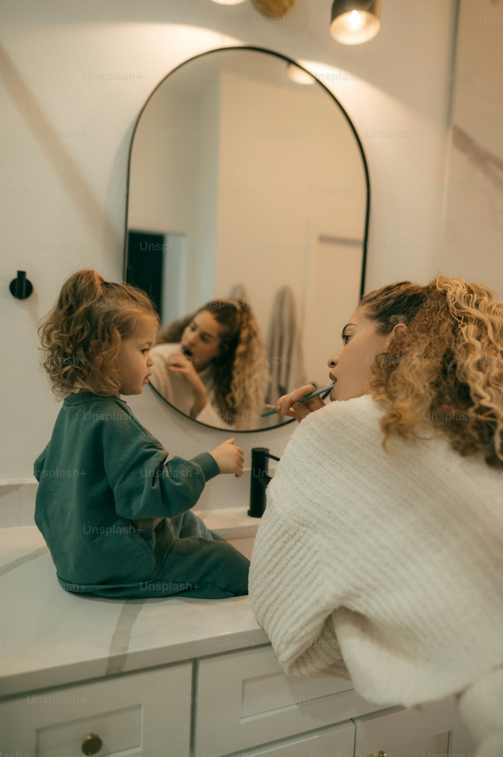 a woman brushing a child's teeth in front of a mirror