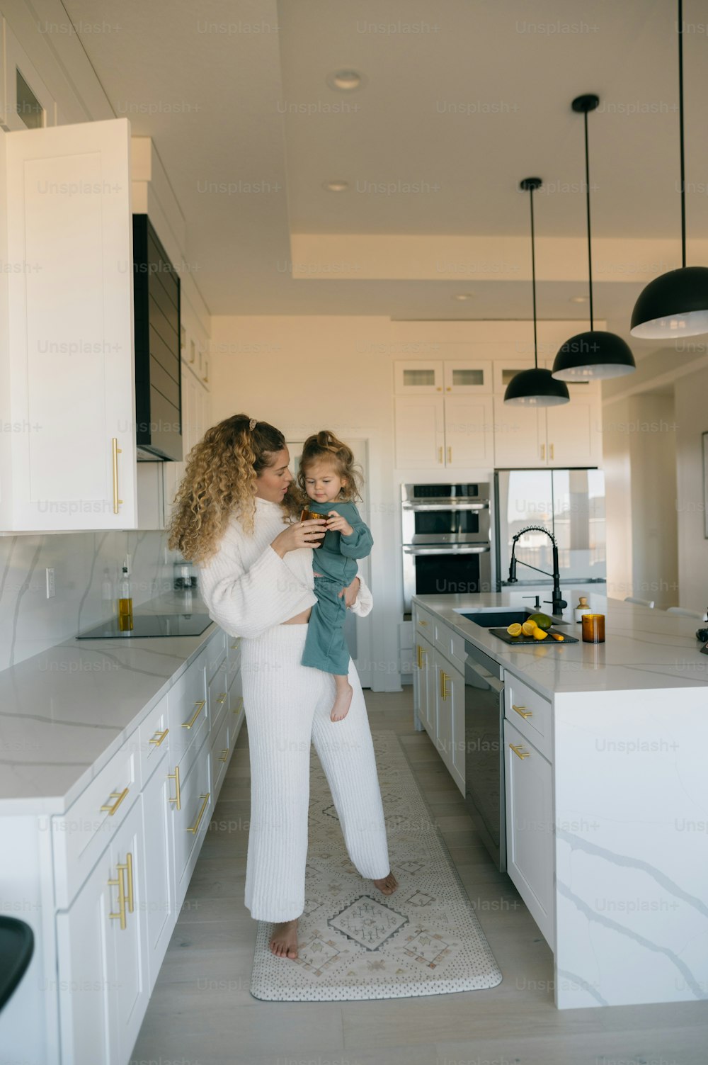 a woman holding a child in a kitchen