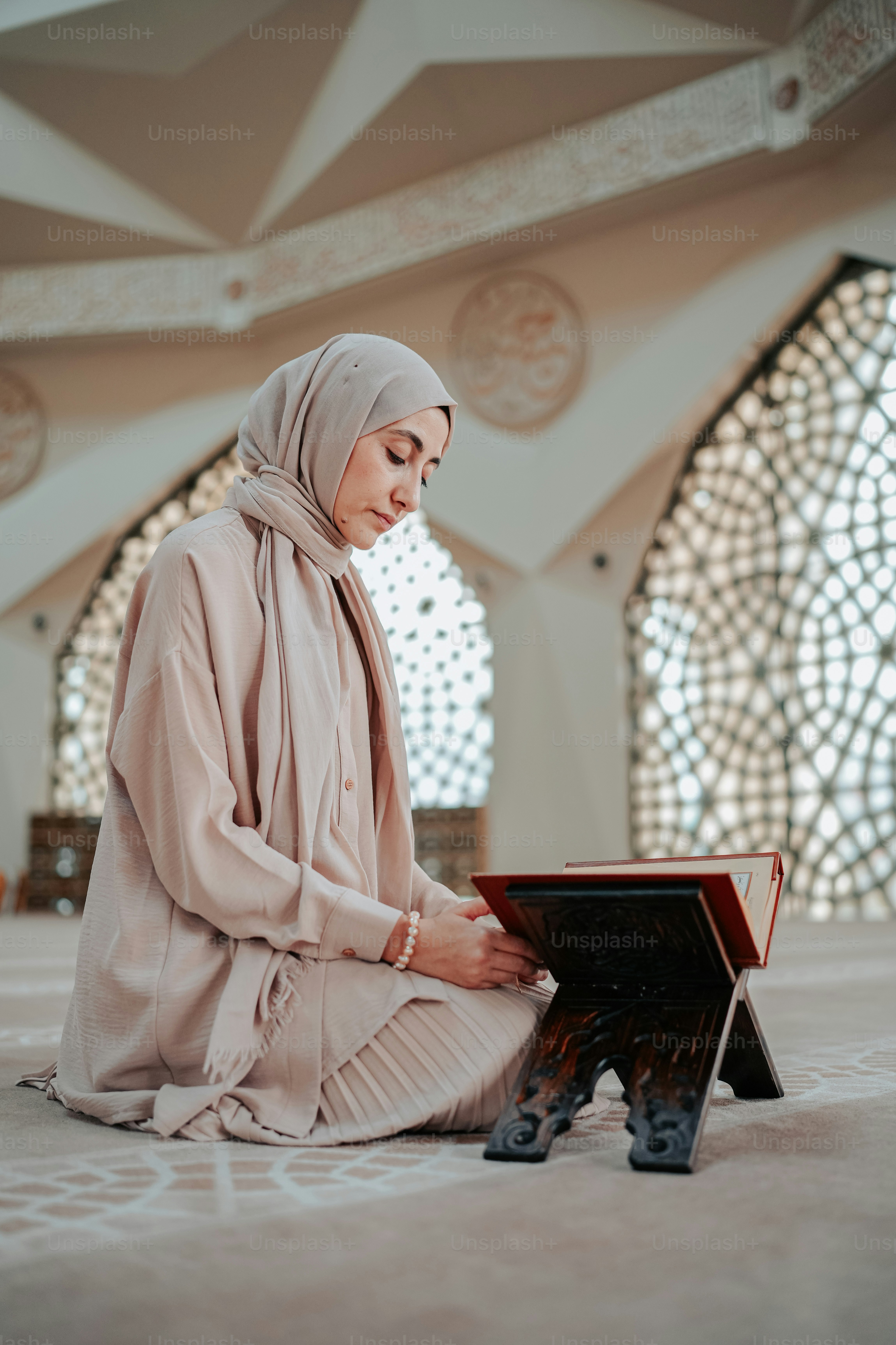 A woman sitting on the floor reading a book photo – Mosque Image on ...