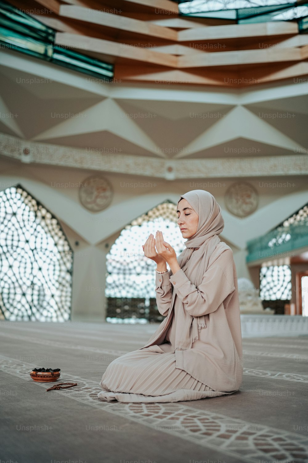 a woman sitting on the floor praying in a mosque
