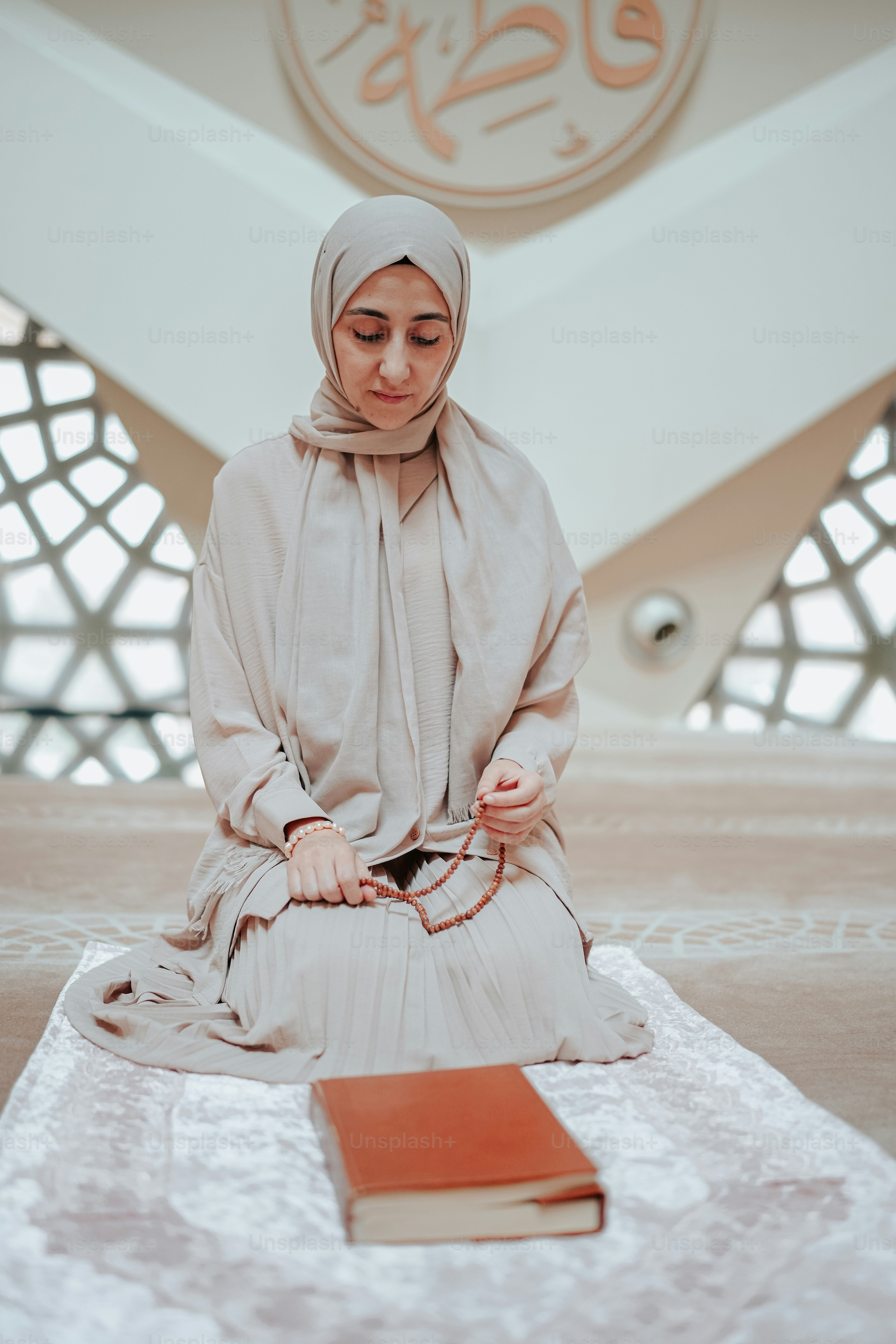 a woman sitting on a mat with a book in front of her
