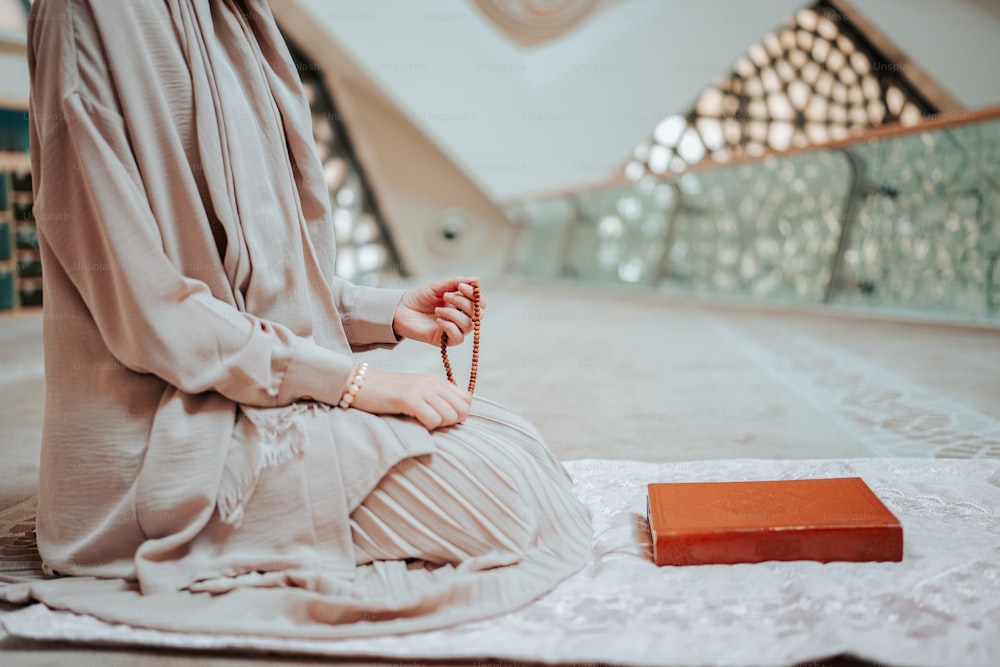 Una donna seduta sul pavimento con un rosario in mano