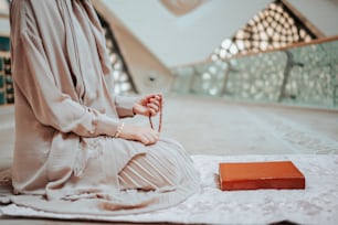 a woman sitting on the floor with a rosary in her hand