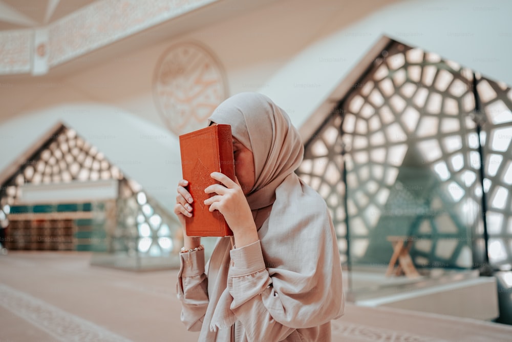 a woman in a hijab is holding a book