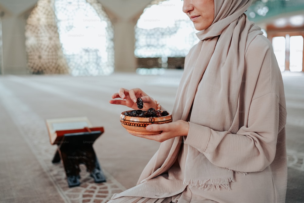 a woman in a hijab holding a bowl of food