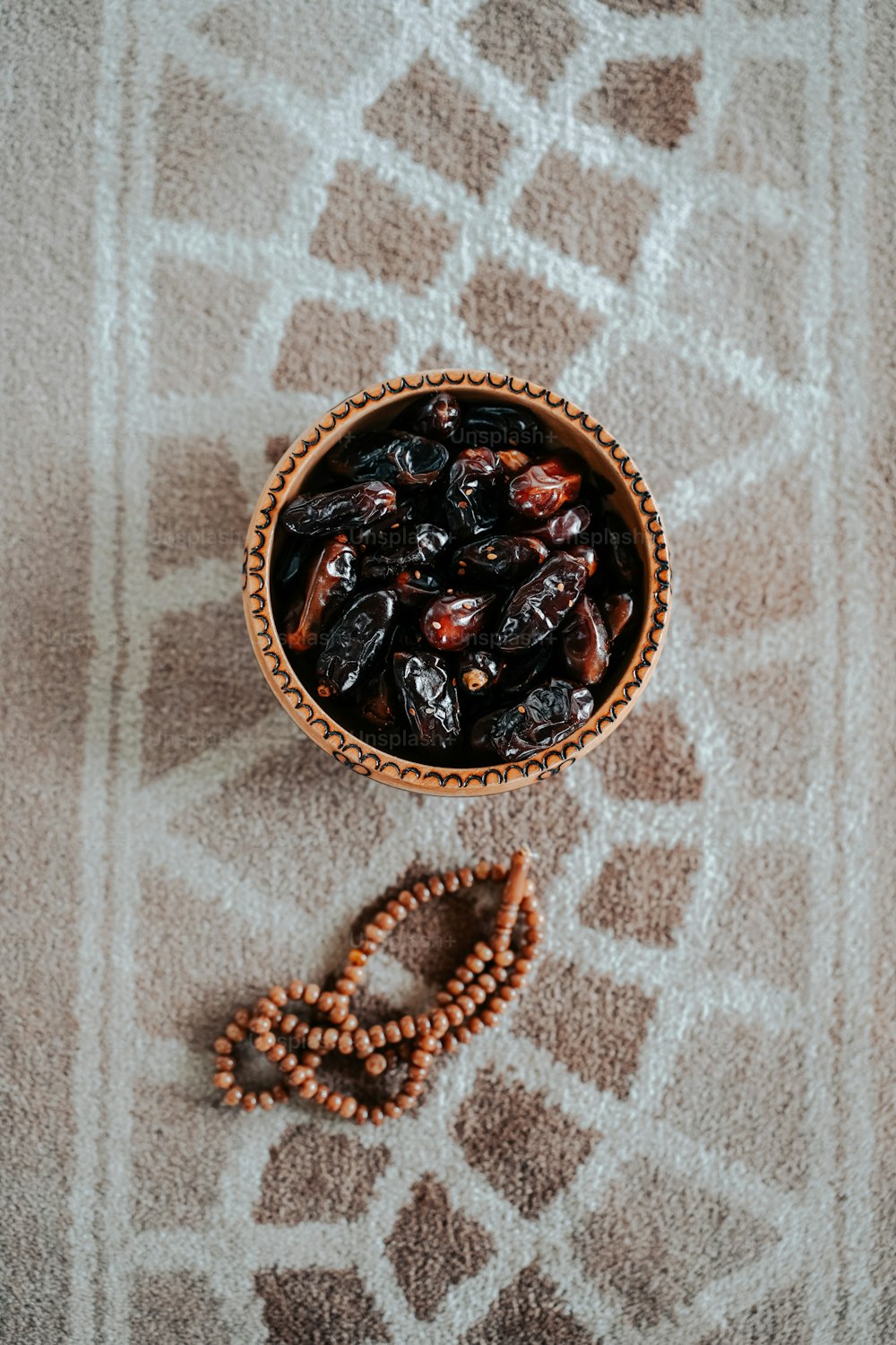 a bowl filled with raisins next to a beaded necklace
