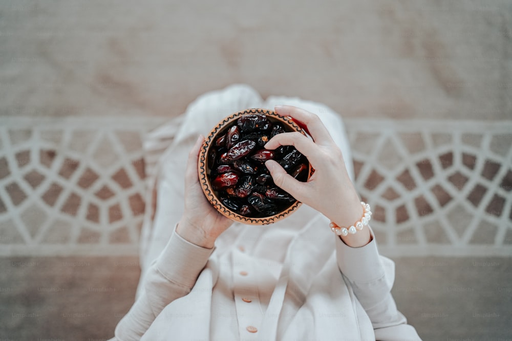 uma mulher segurando uma tigela de cerejas em suas mãos