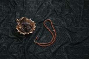 un collier de perles en bois et un objet métallique sur un tissu noir