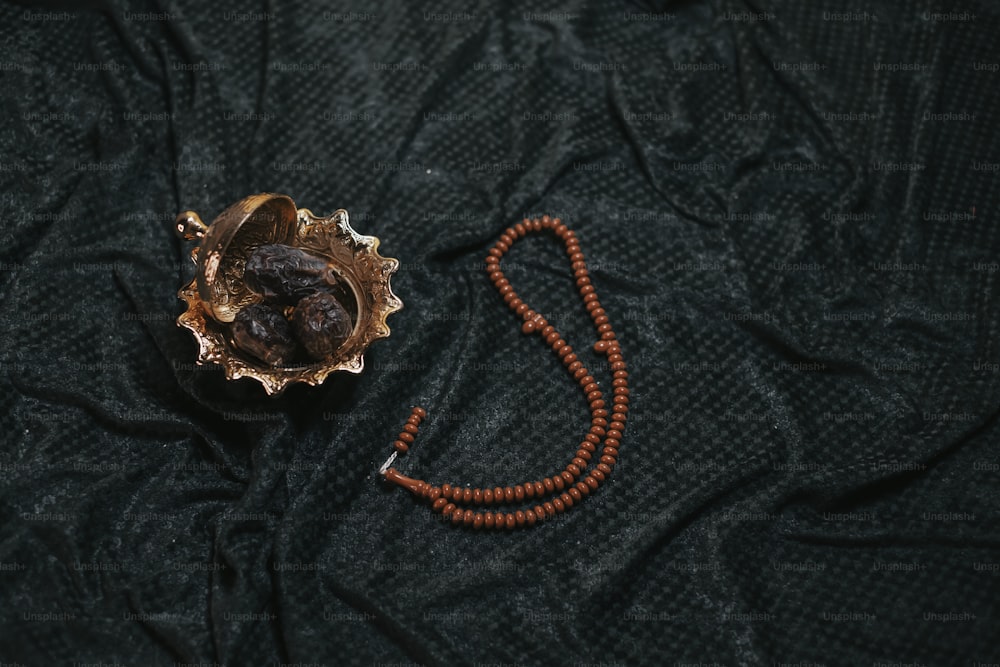 a wooden bead necklace and a metal object on a black cloth