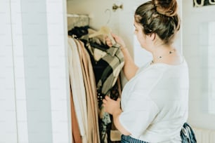 a woman looking at clothes in a closet