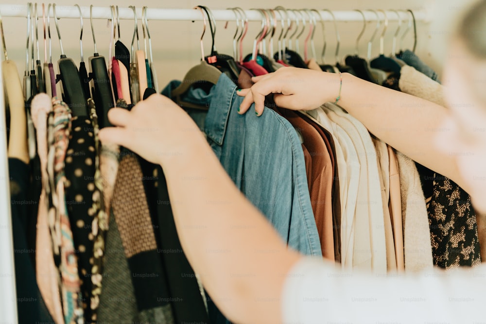 a woman is looking at a rack of clothes