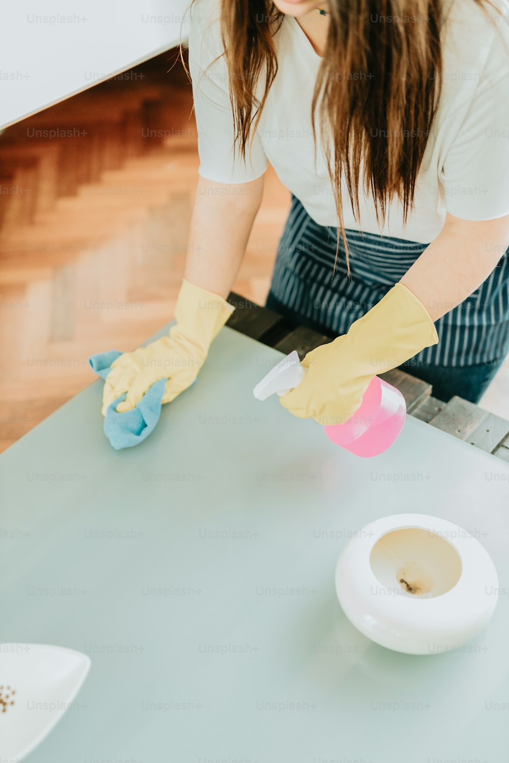 a woman in yellow gloves cleaning a table