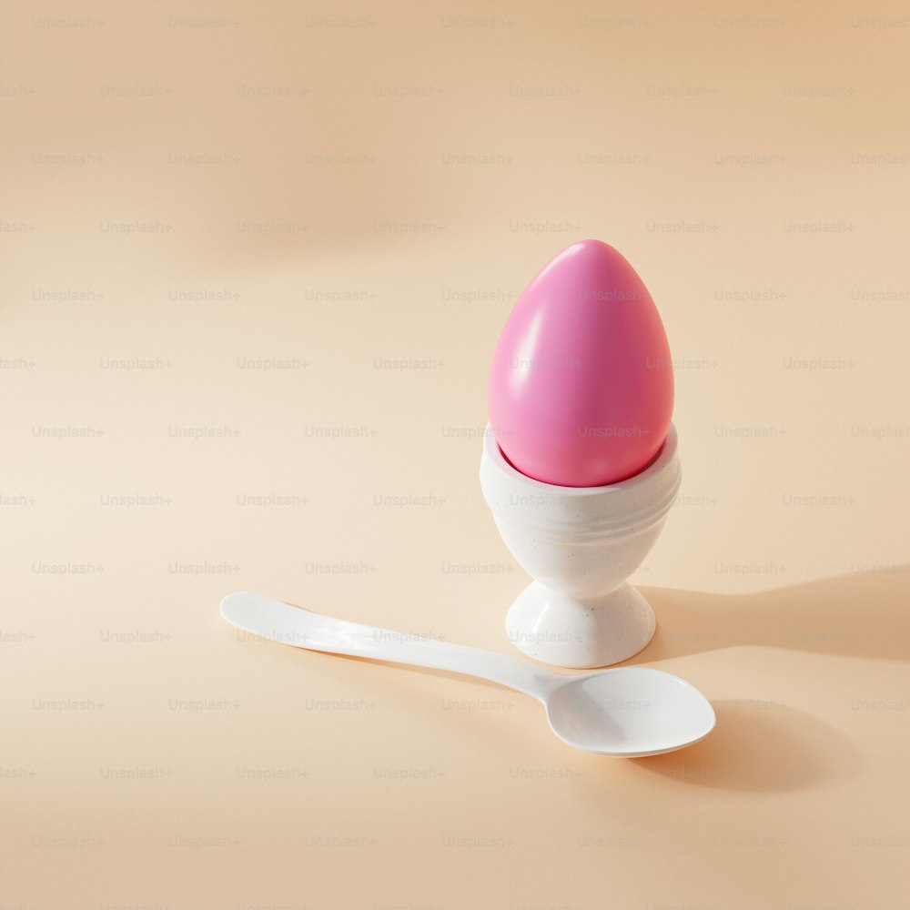 a pink egg sitting on top of a white spoon