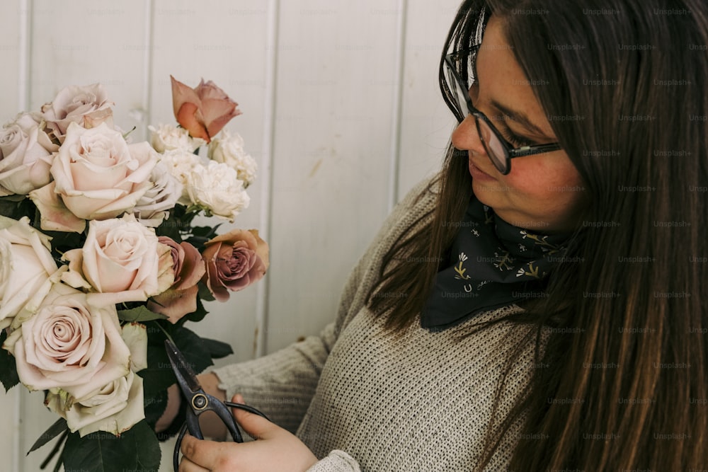 a woman cutting a bouquet of flowers with a pair of scissors