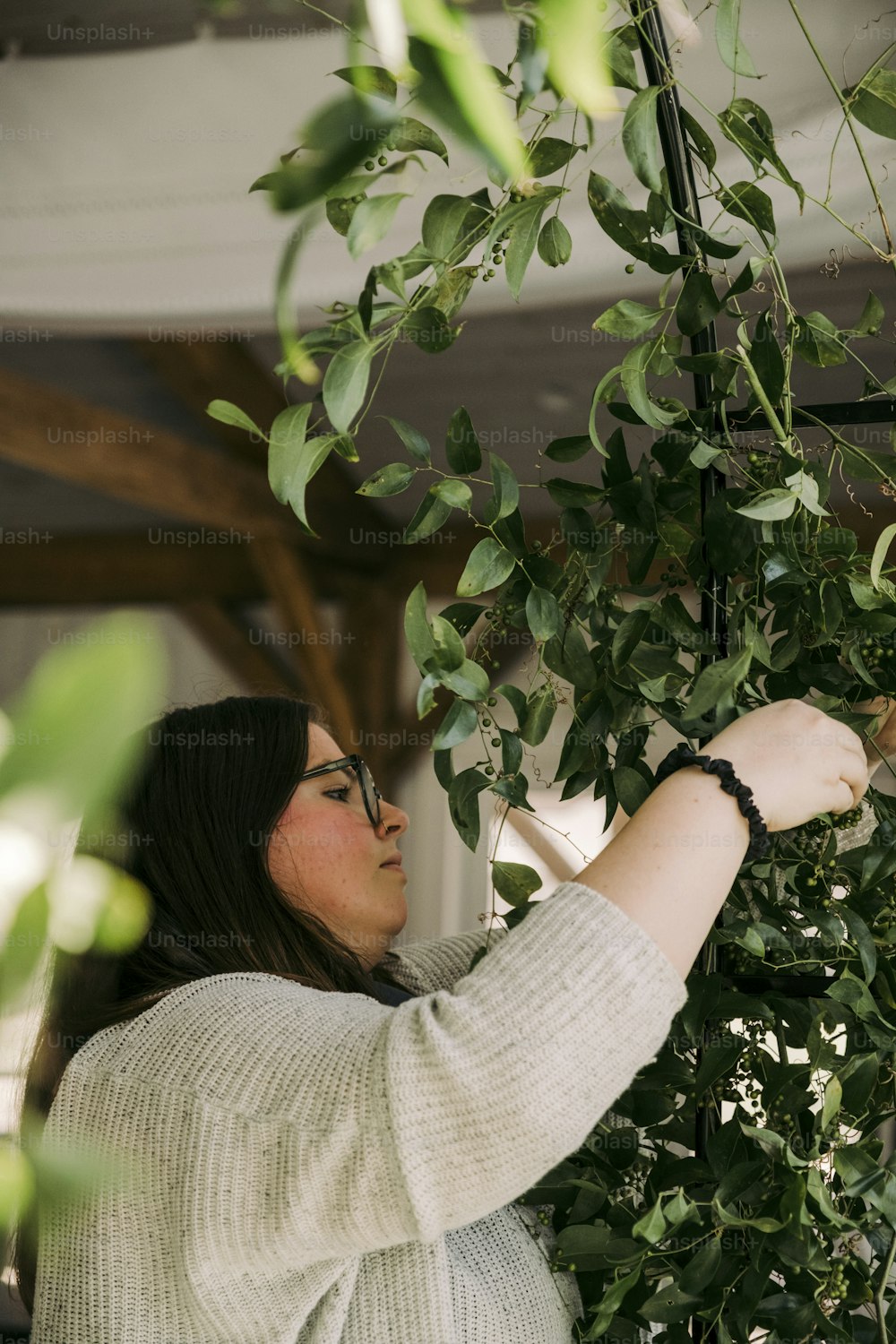 Una mujer con un suéter blanco está mirando una planta