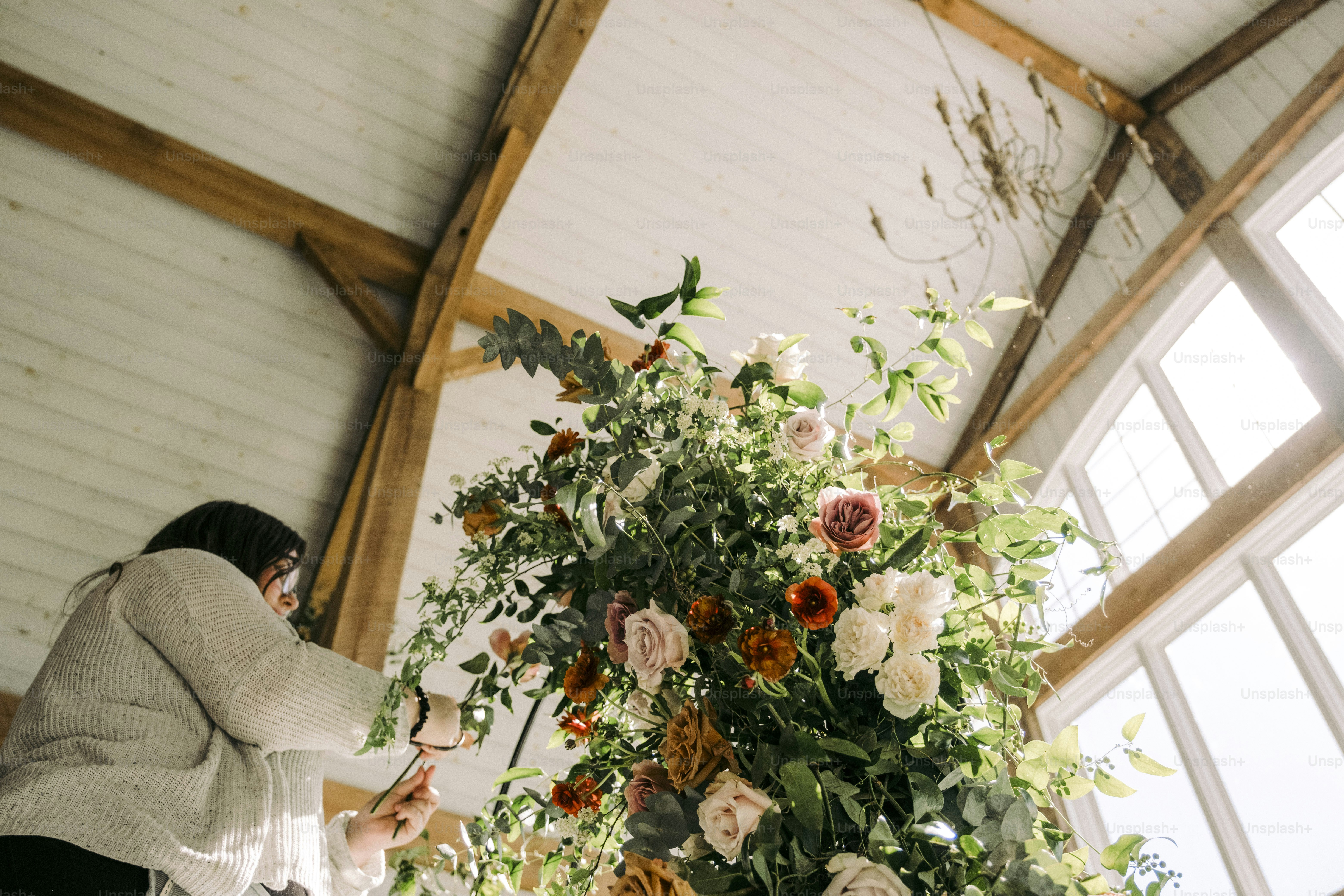 Eine Frau steht neben einer hohen Vase voller Blumen