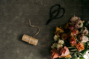 a spool of twine next to a bouquet of flowers