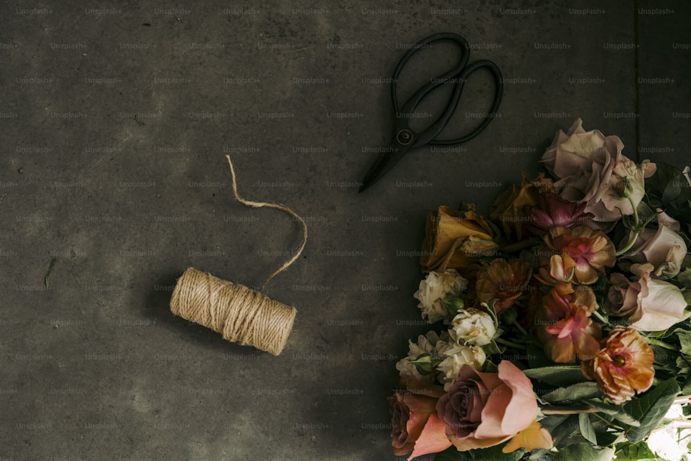 a spool of twine next to a bouquet of flowers