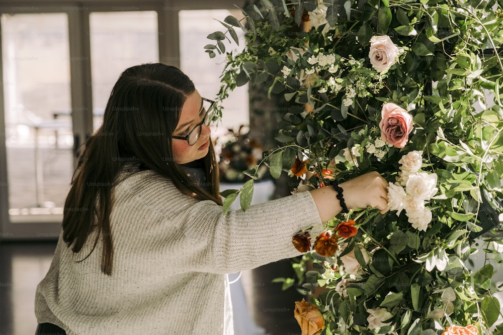 a woman is arranging flowers on a wall