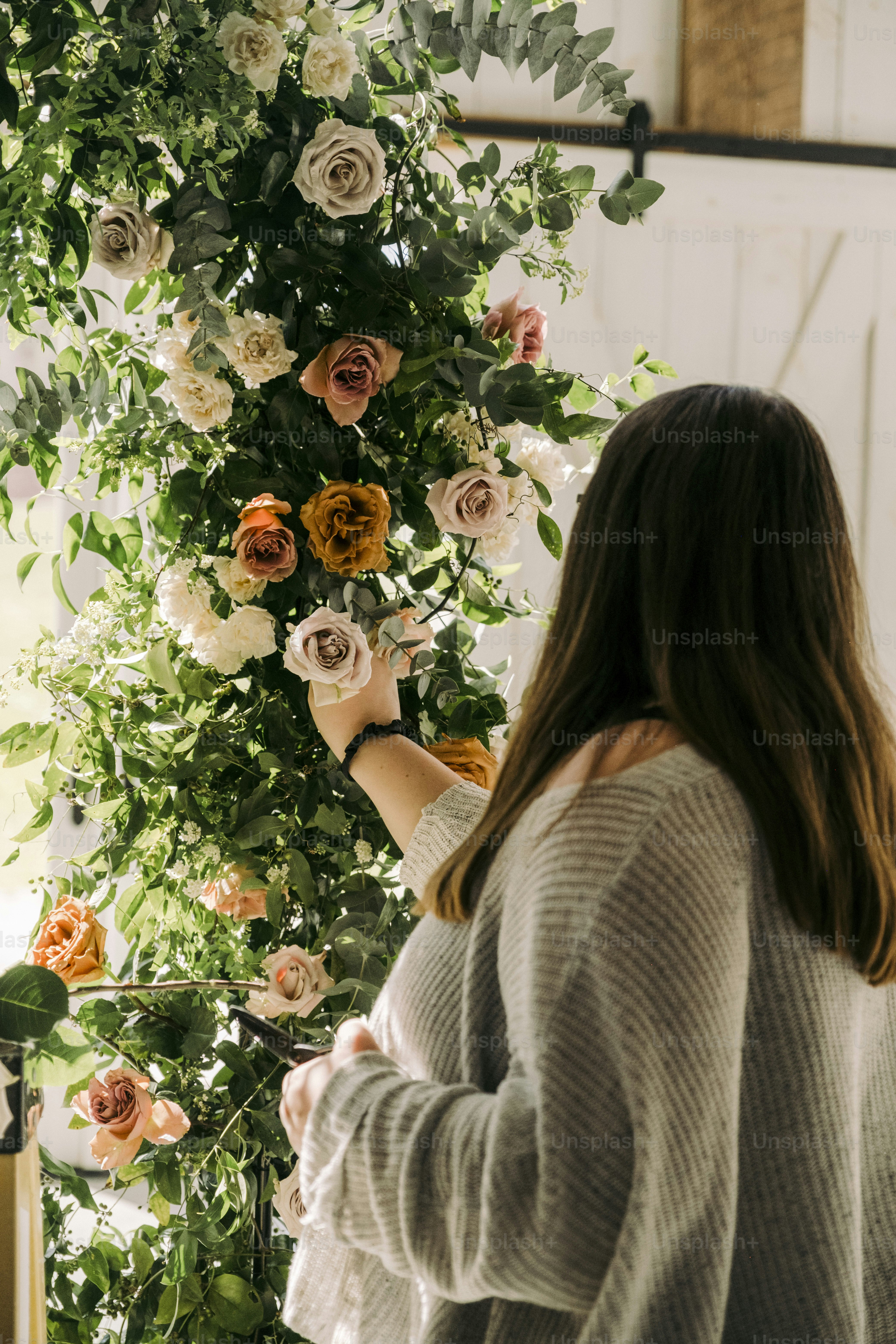 a woman arranging flowers on a wall