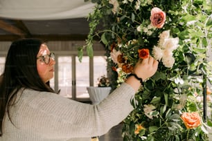 Eine Frau arrangiert Blumen an einer Wand