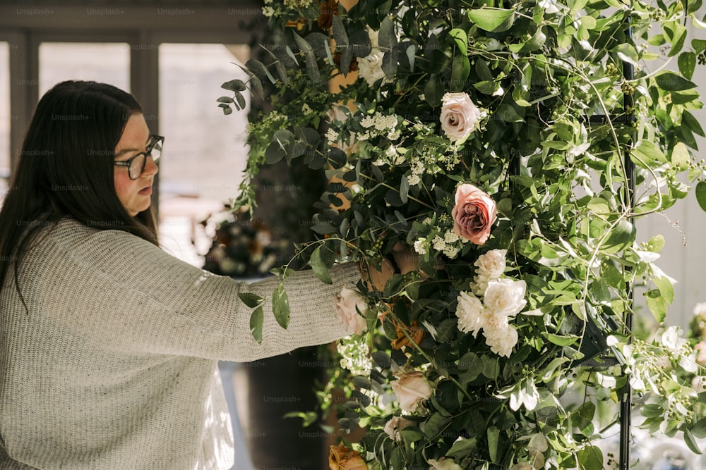 a woman is arranging flowers on a wall