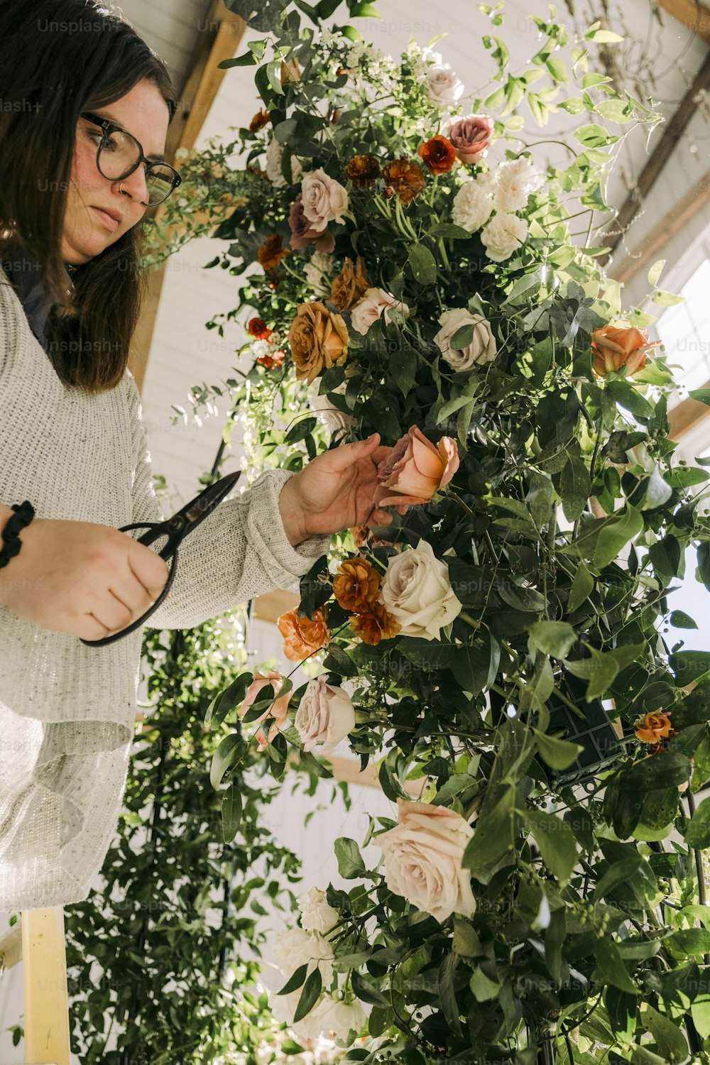 a woman cutting flowers with a pair of scissors