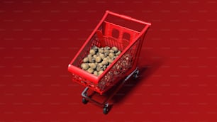 a red shopping cart filled with potatoes on a red surface
