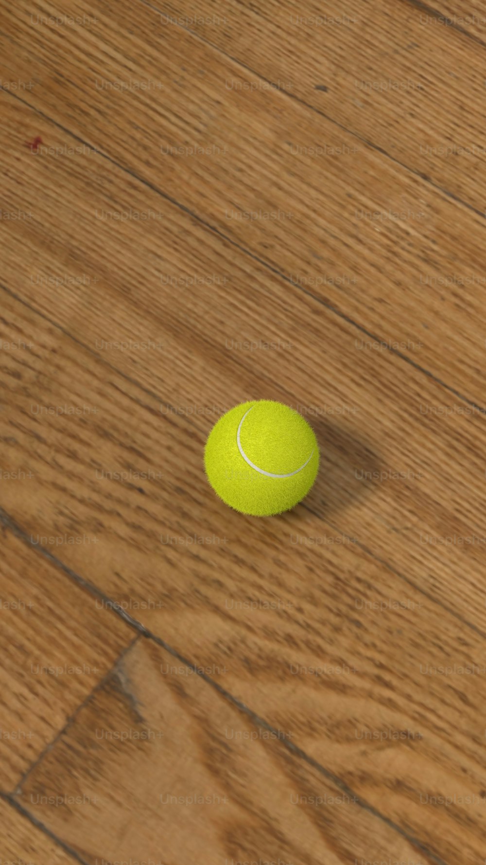 Una pelota de tenis sentada en un piso de madera