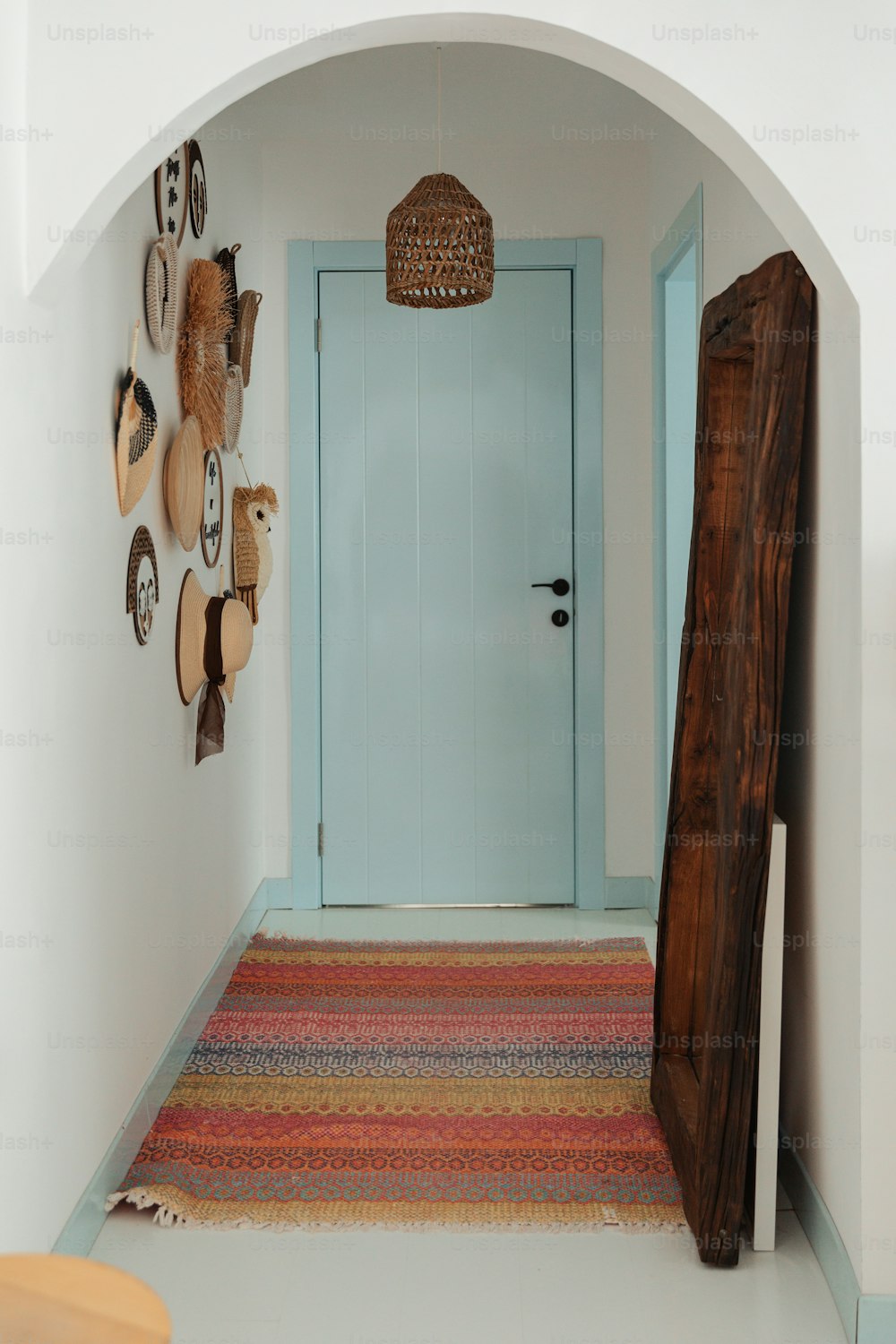 a hallway with a blue door and several hats on the wall