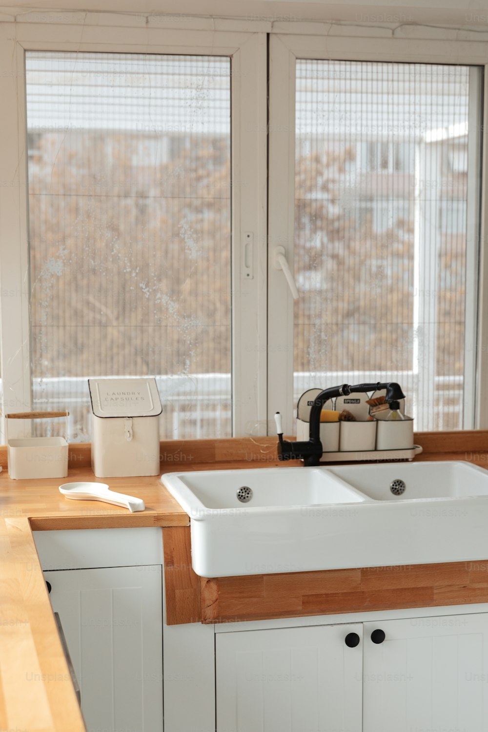 un lavello bianco della cucina seduto sotto una finestra
