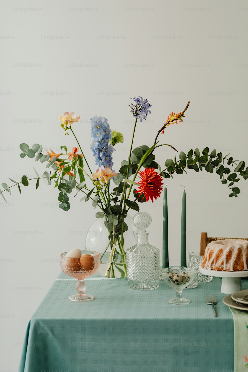 una mesa cubierta con un pastel y un jarrón lleno de flores