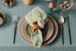 a place setting with a napkin, flowers, and eggs