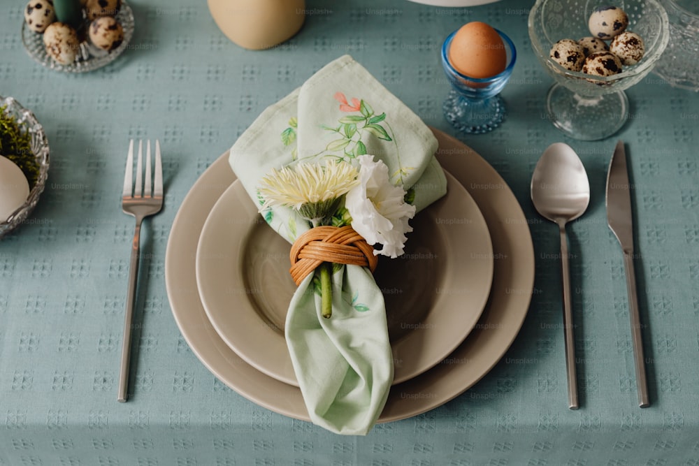 ein Gedeck mit Serviette, Blumen und Eiern