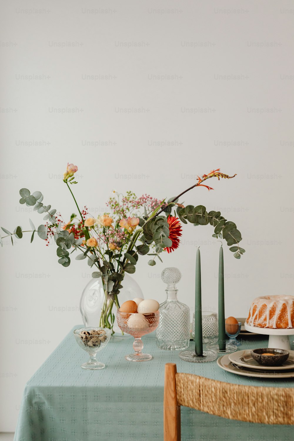 a table topped with a cake and a vase filled with flowers