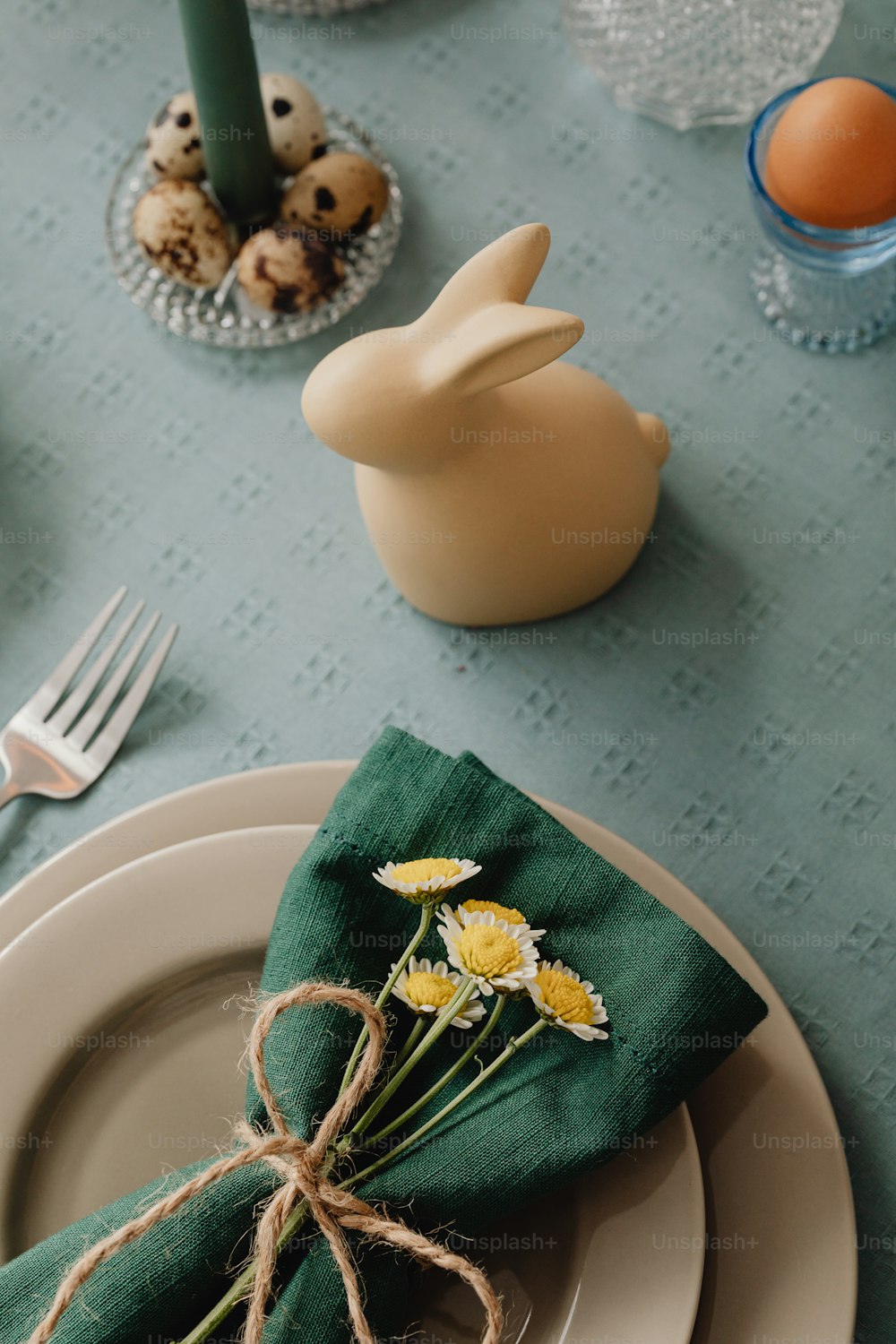 a place setting with a green napkin and yellow flowers