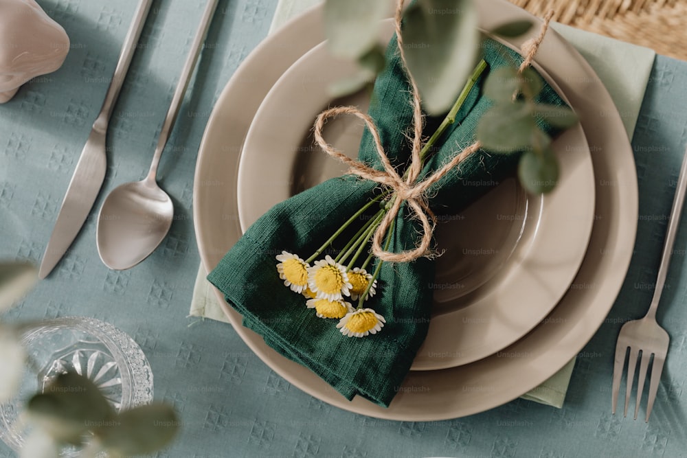 a place setting with napkins and flowers on a plate