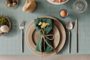 a place setting with a green napkin tied with twine