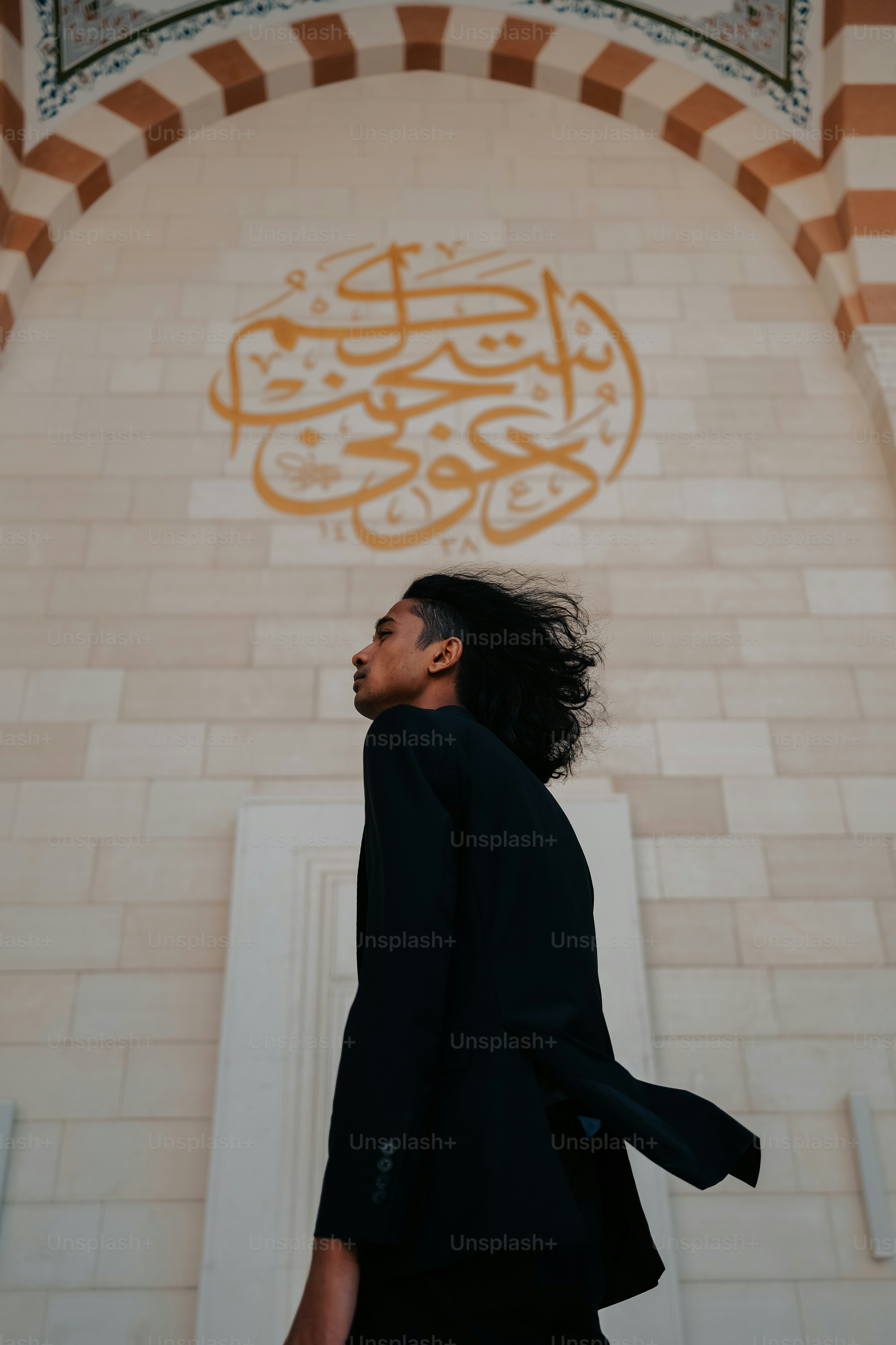 a man with long hair walking in front of a building