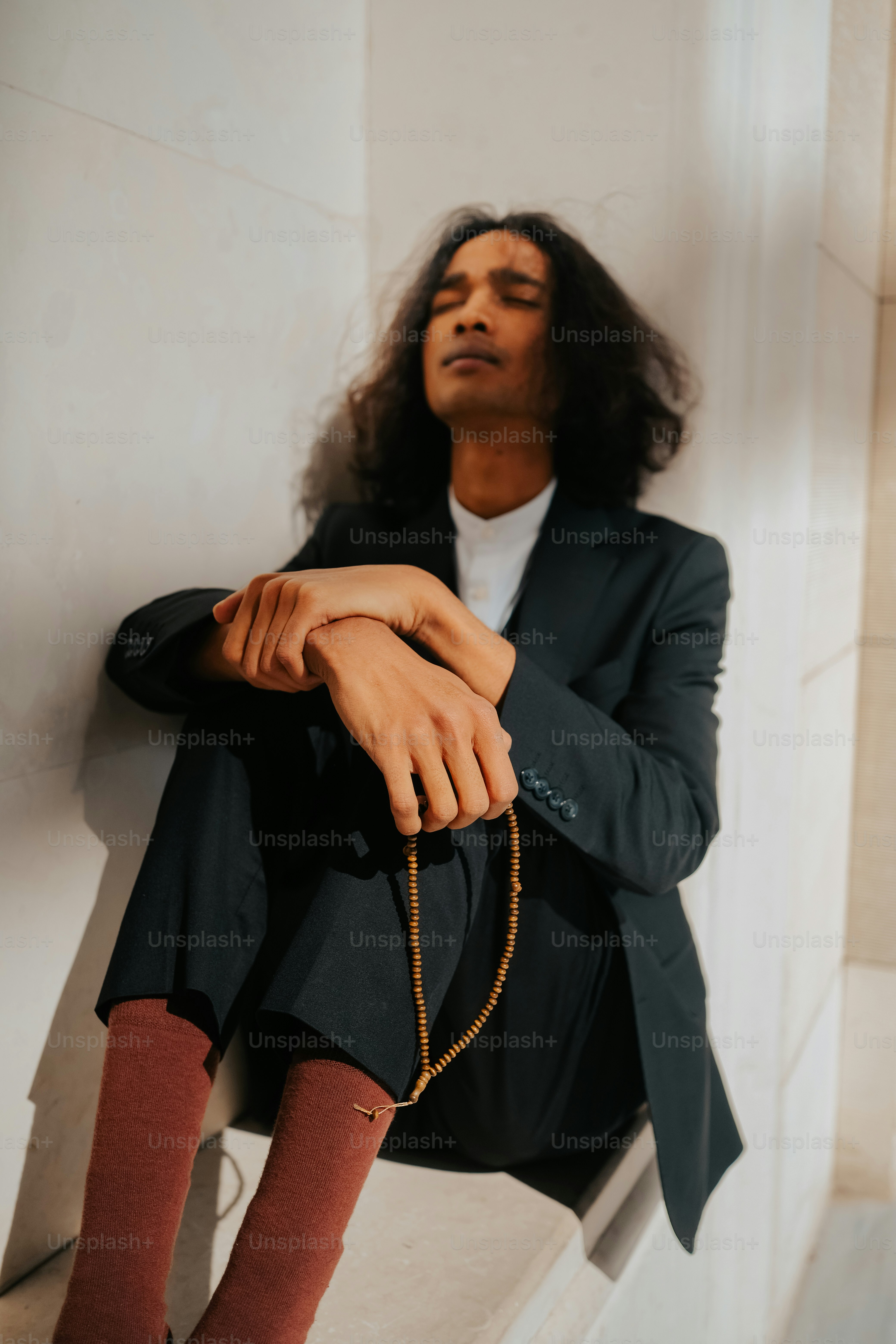 a man with long hair sitting on a ledge