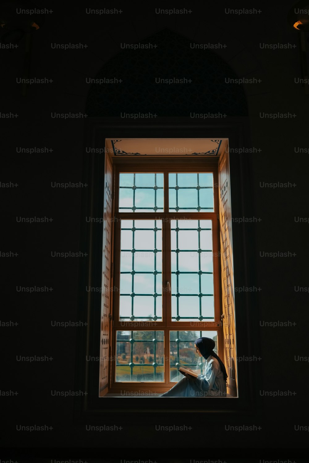 a woman sitting in front of a window reading a book