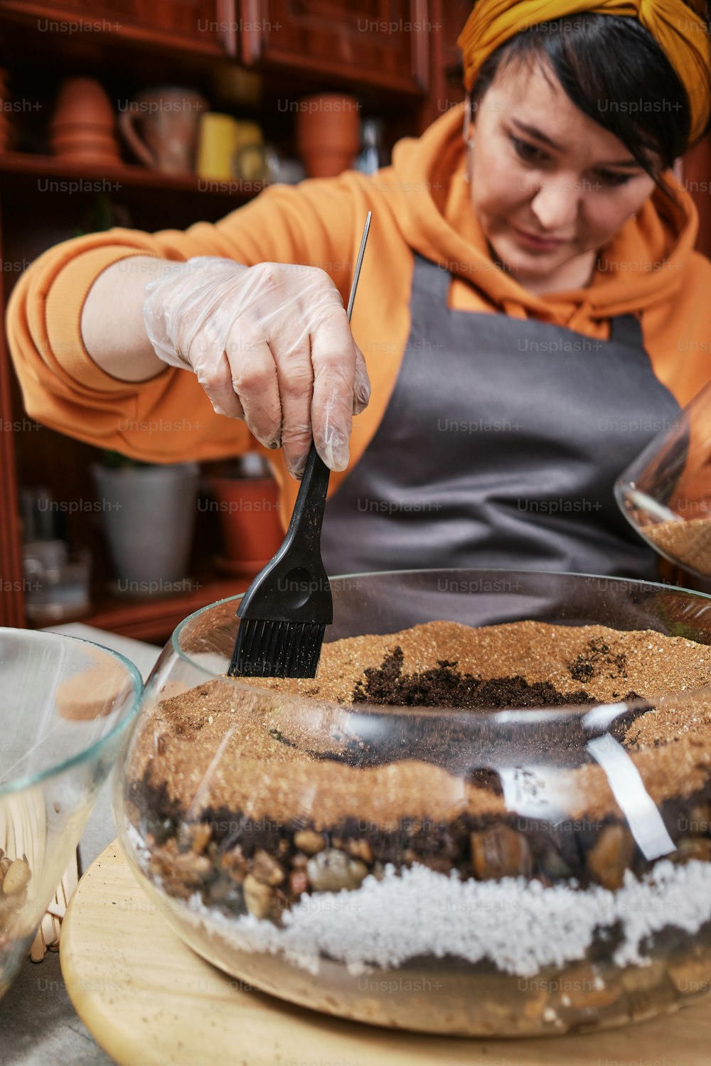 a woman in an orange hoodie is cutting a cake