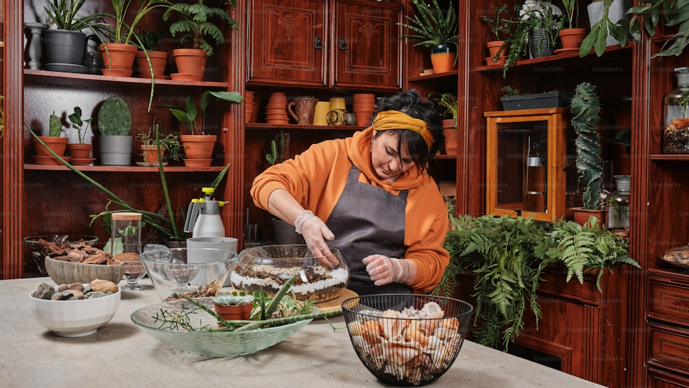 a woman in an orange jacket preparing food in a kitchen
