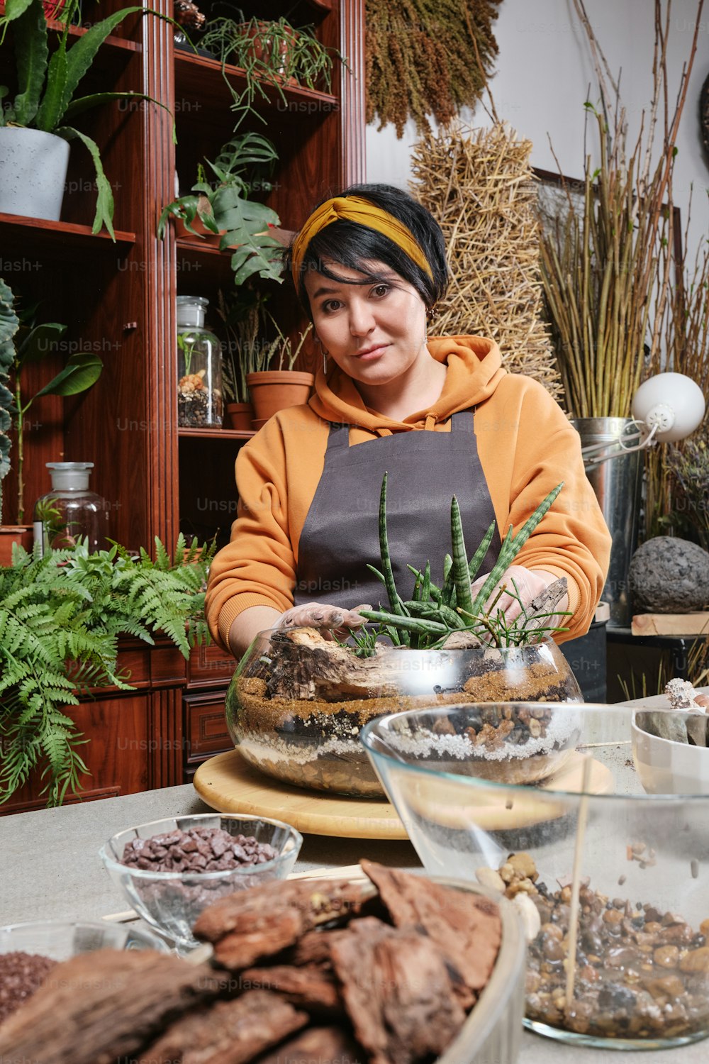 a woman standing behind a table filled with plants