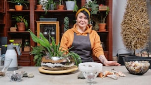 a woman sitting at a table with a potted plant