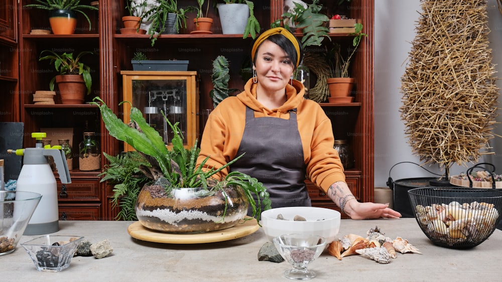 a woman sitting at a table with a potted plant