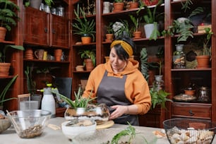 a woman standing in front of a shelf filled with potted plants