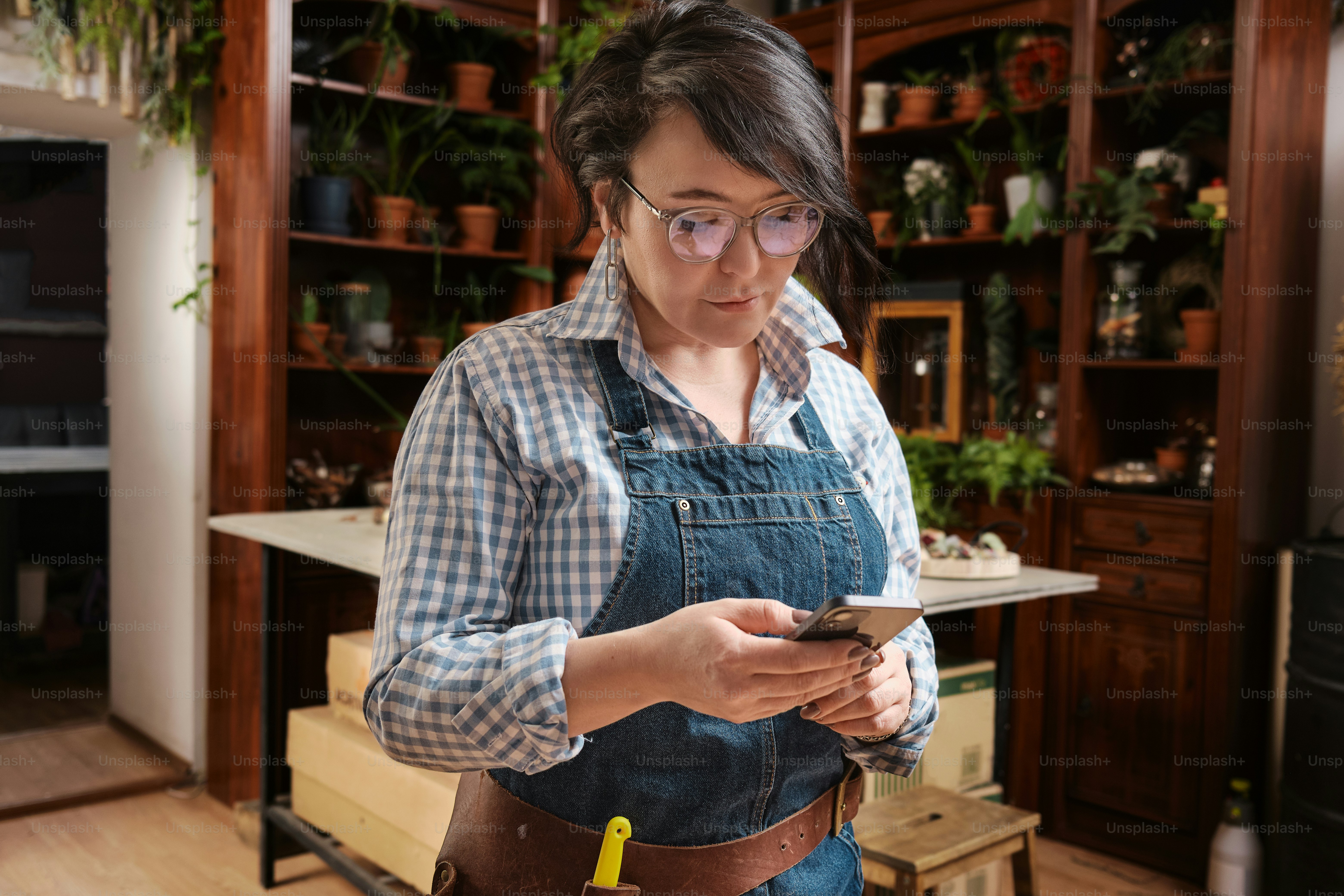 uma mulher de macacão segurando um telefone celular
