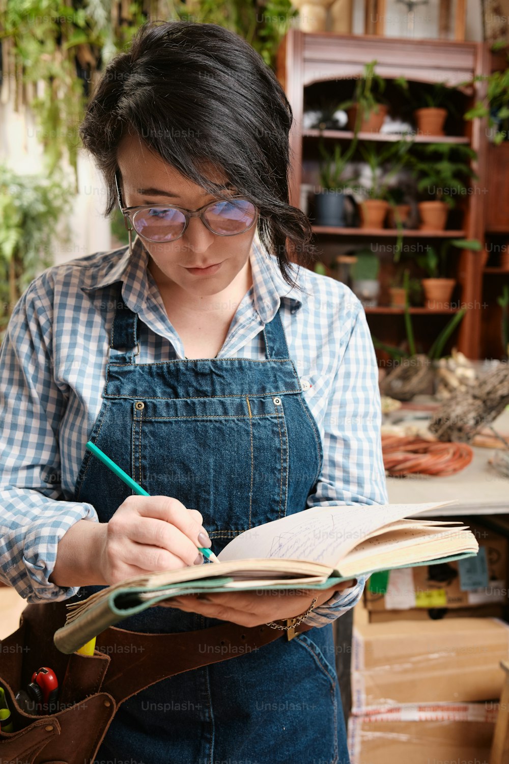 a woman in overalls writing in a book