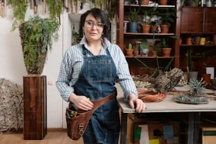 a woman is holding a tool belt in a room full of potted plants
